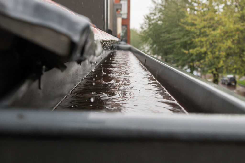 Water from the roof drains into the gutter, rainy weather, commercial gutter installation on display