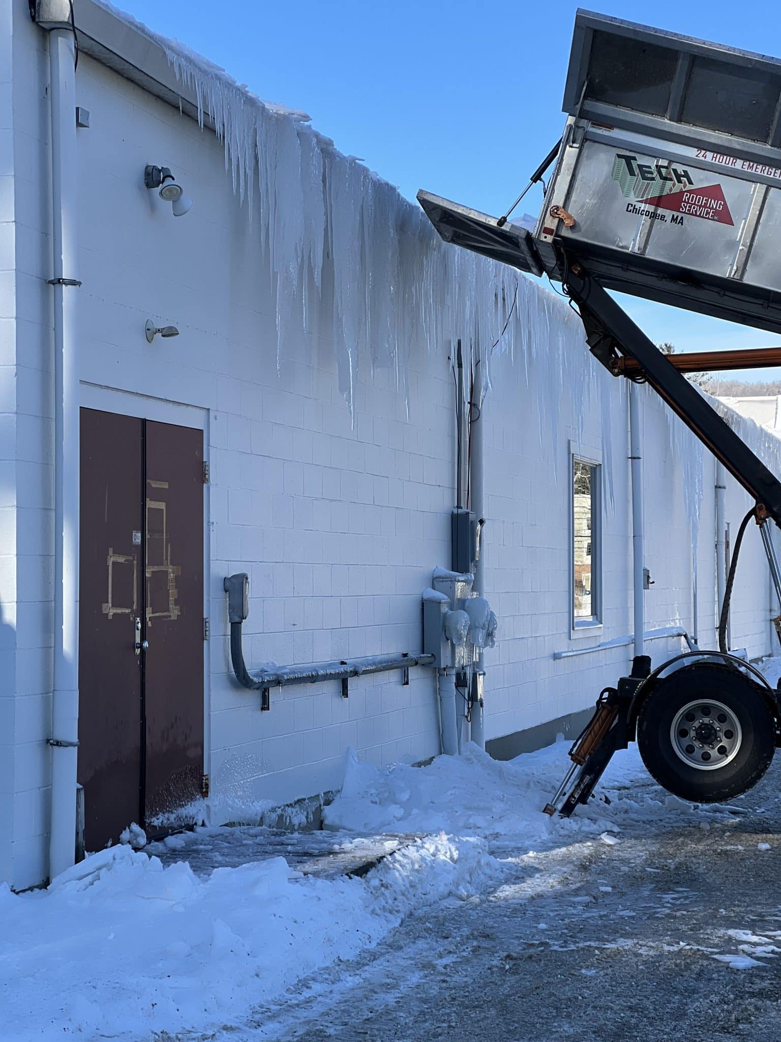 tech roofing dumpster being lifted up to roof to help assist with snow removal services