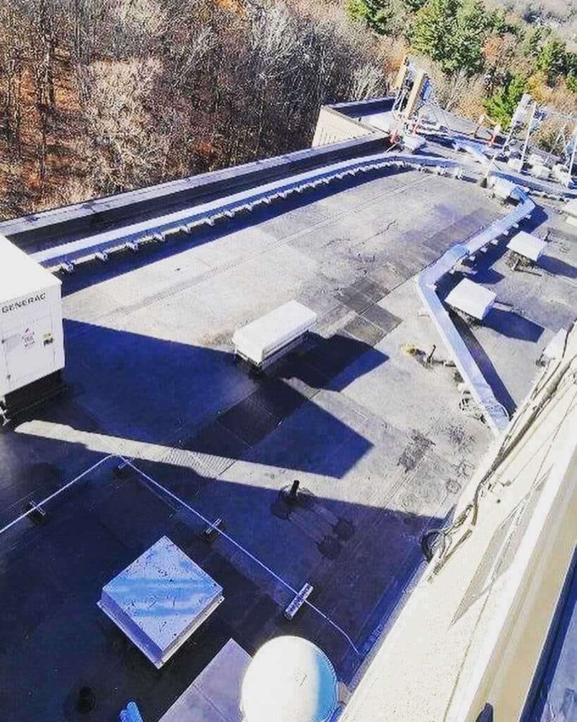 Completed EPDM roof replacement at Coes Pond Apartments in Worcester, MA showing the black membrane roof, parapet walls, and rooftop equipment.